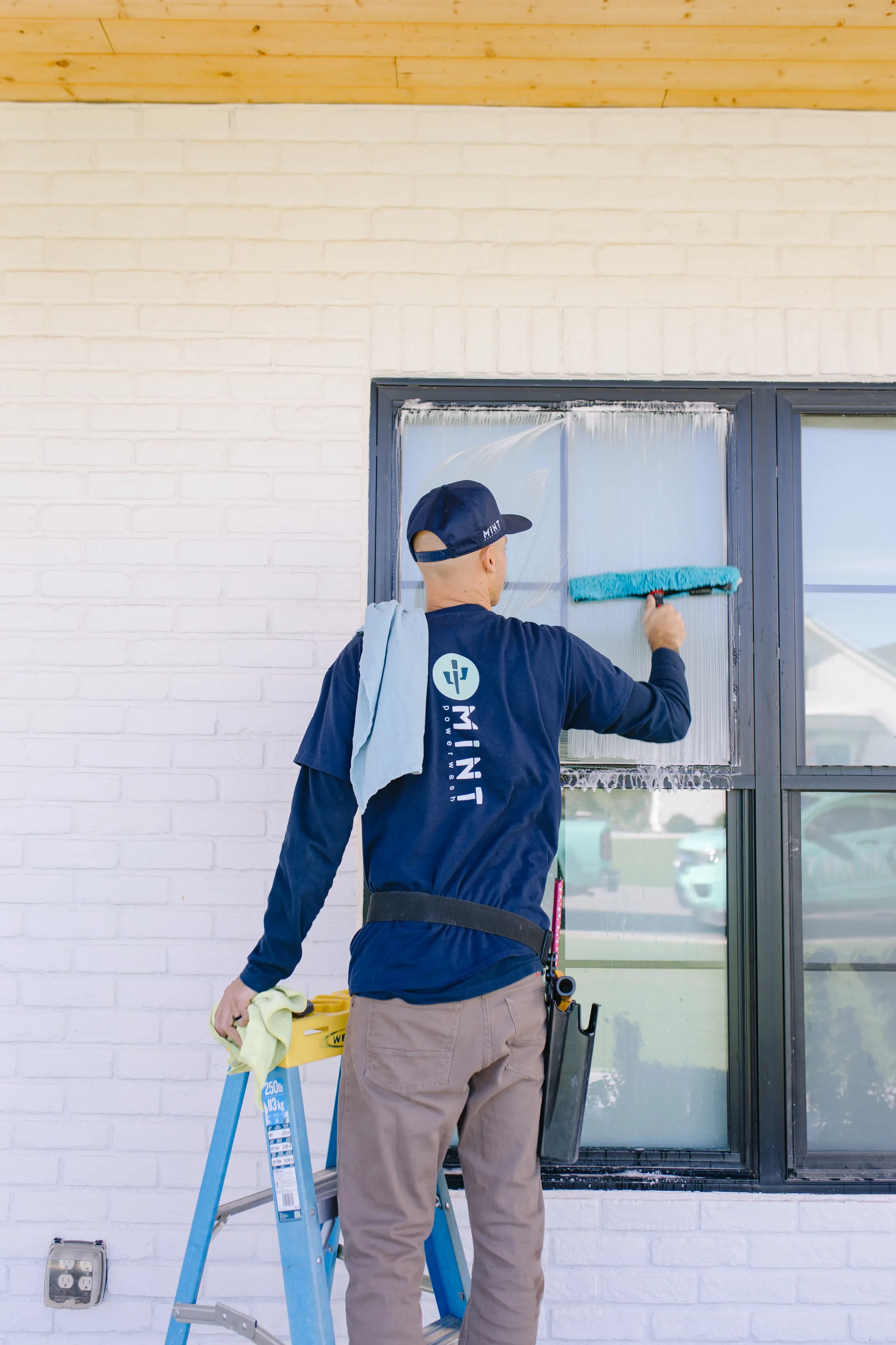 MiNT technician squeegeeing glass in a MiNT shirt