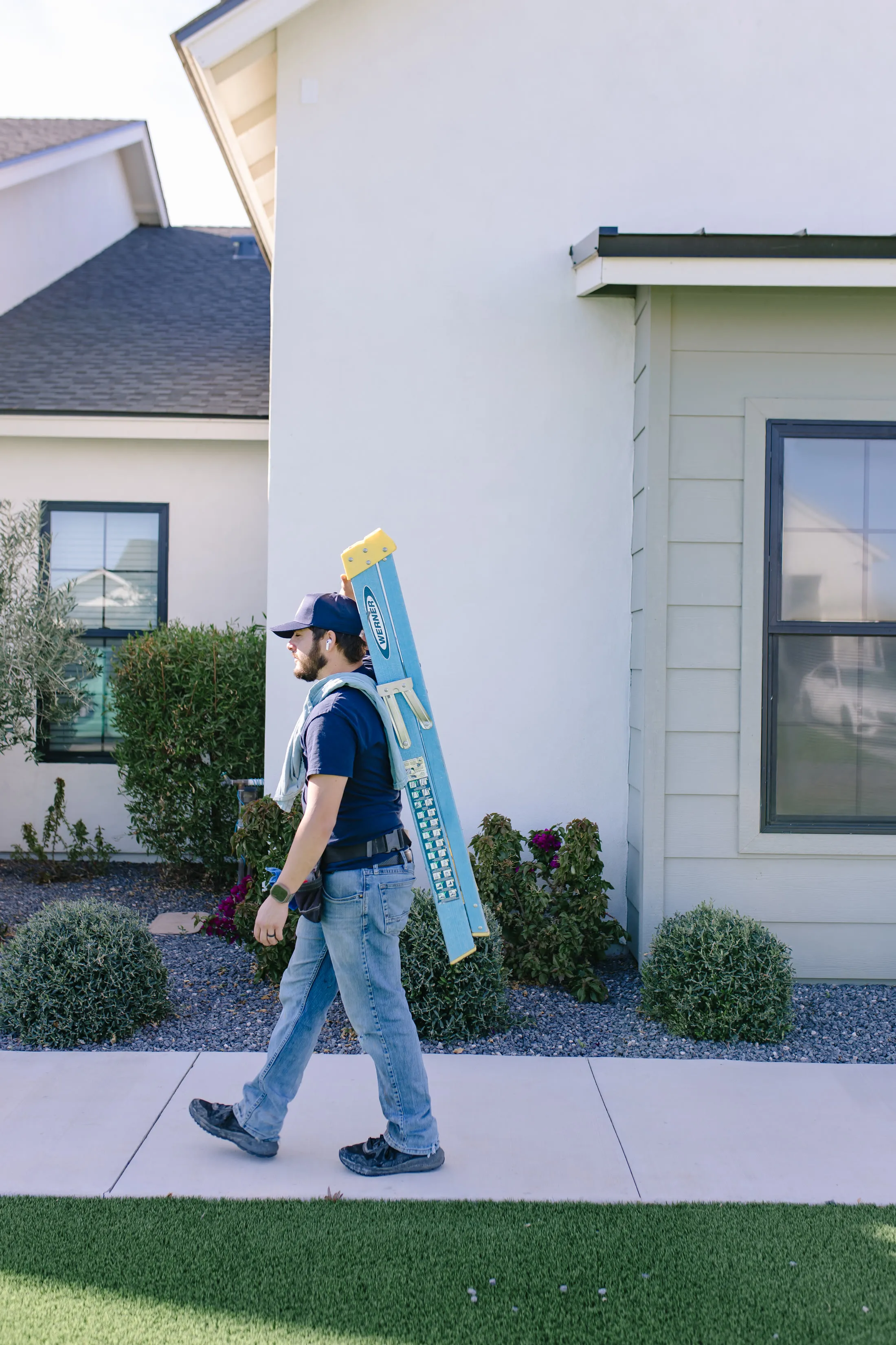 MiNT technician carrying a ladder up a walkway