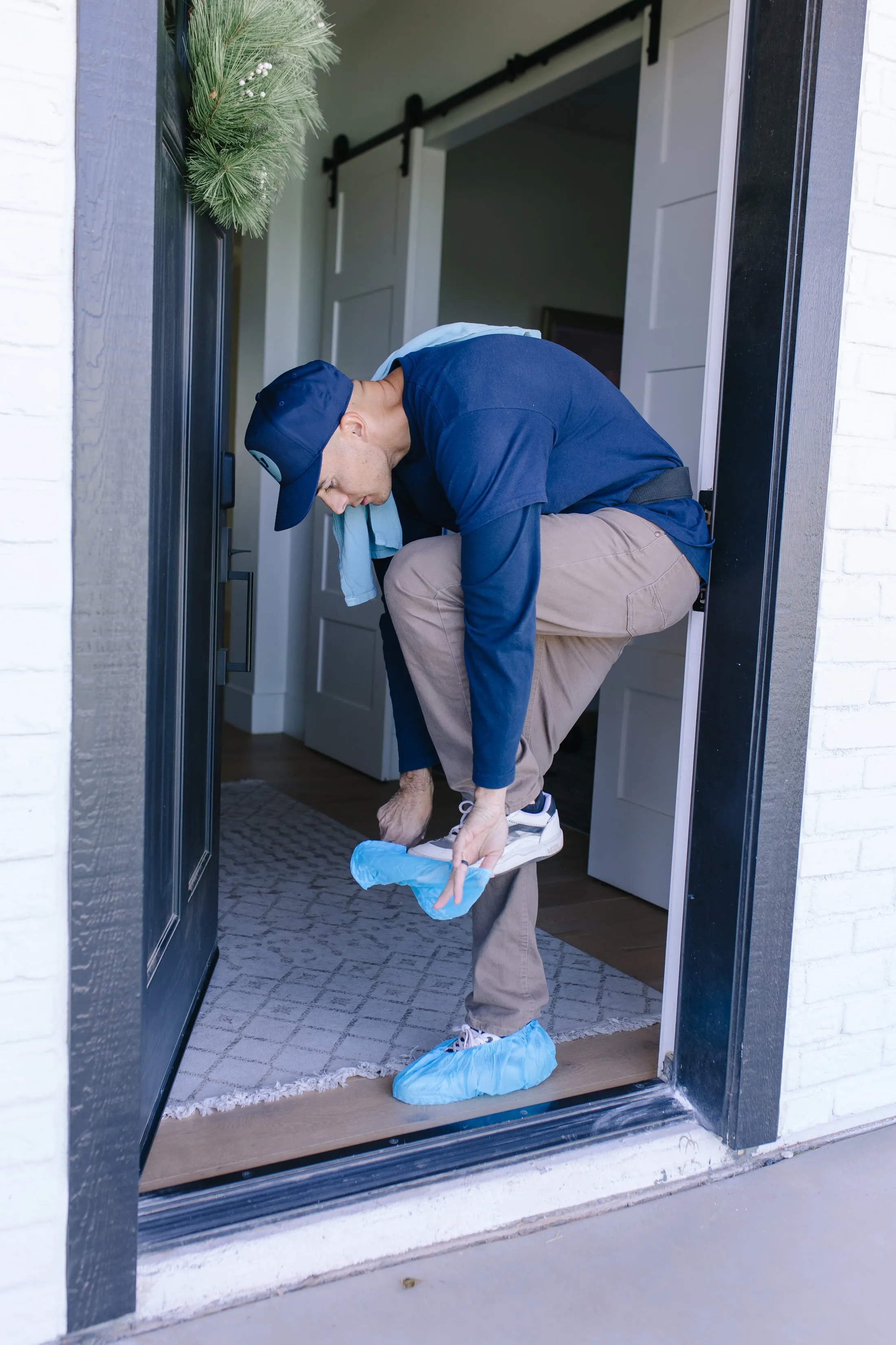 MiNT technician putting on shoe covers at a front door